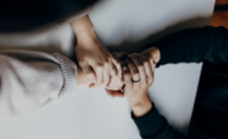 four people holding hands together